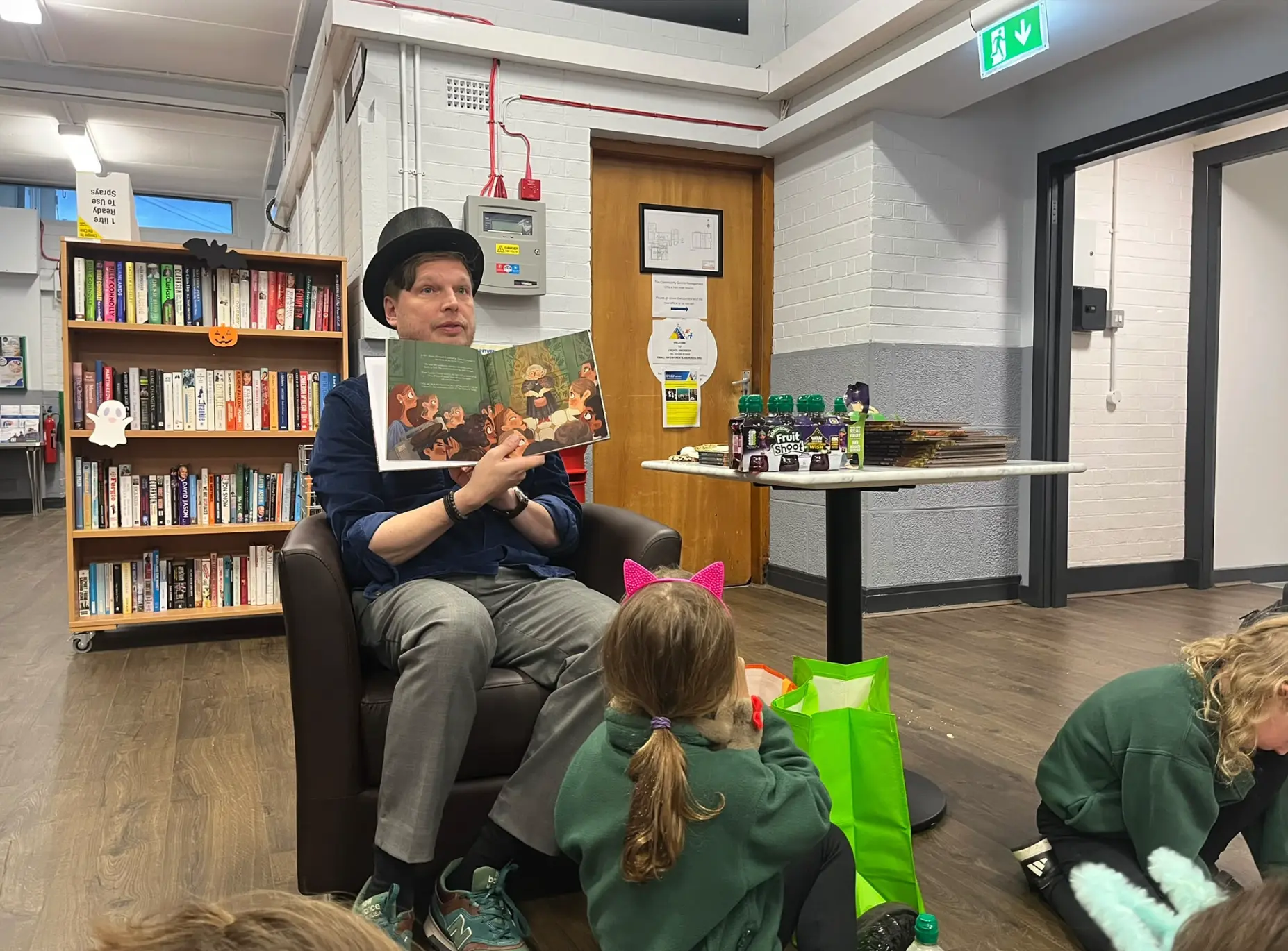 Aldo de Pape in a top hat reading The Magical Manacles to children